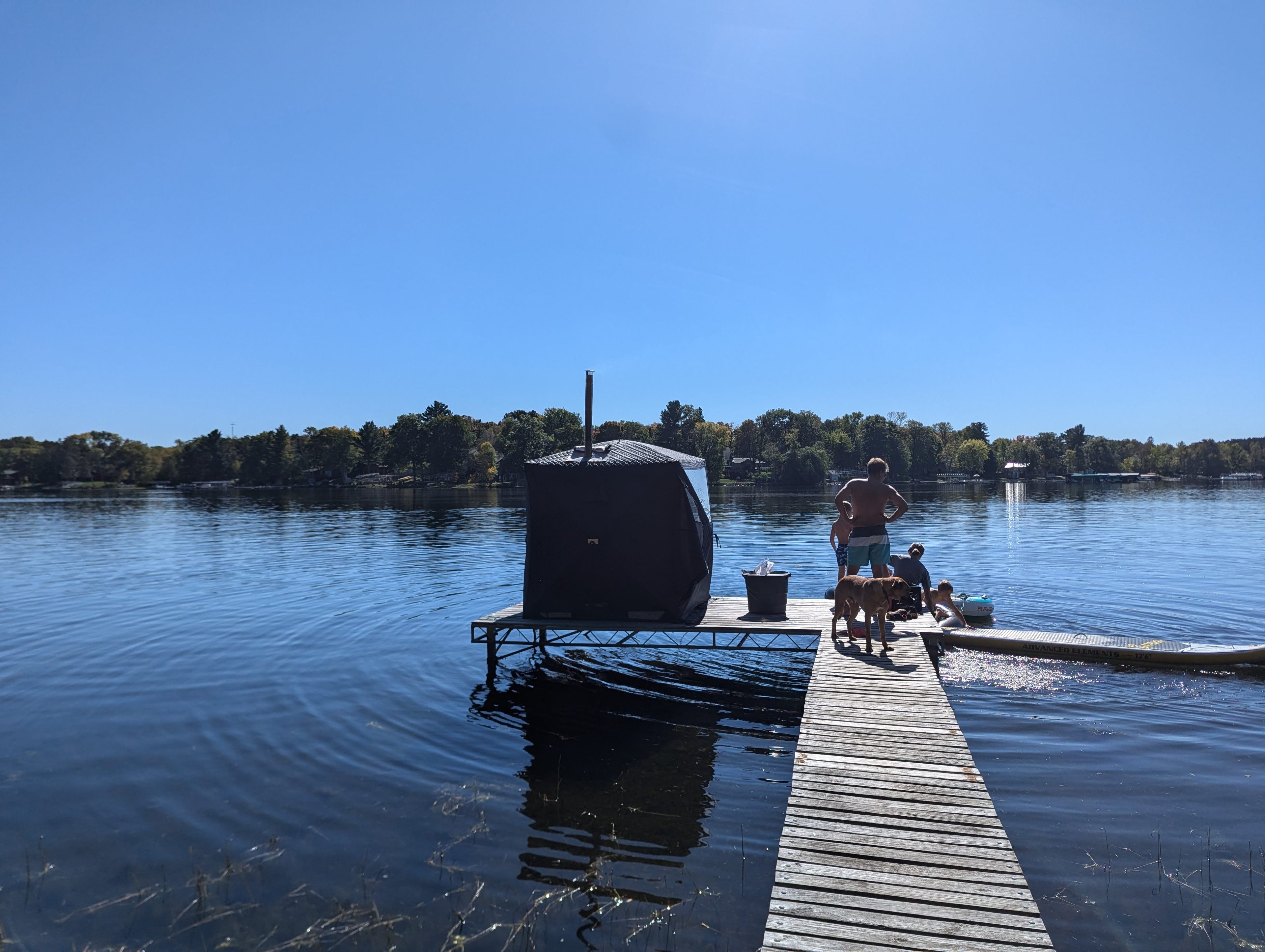 A sauna tent set up for sweat at the end of a dock on a beautiful lake. Recovery time after workout.